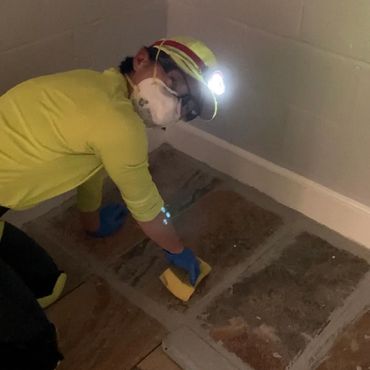 A woman grouts ceramic floor tile.