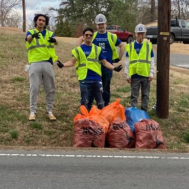 Young people standing together after picking up trash from the road.