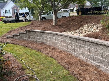 Block retaining wall with drainage swale and pine straw installation at a home in Braselton, GA