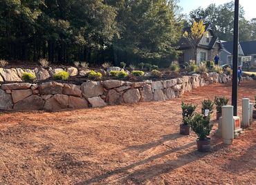 Large boulder retaining wall with tiered landscape beds at a new construction home in Jefferson, GA