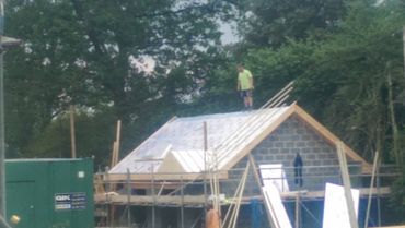 A person standing on the roof of a building under construction.