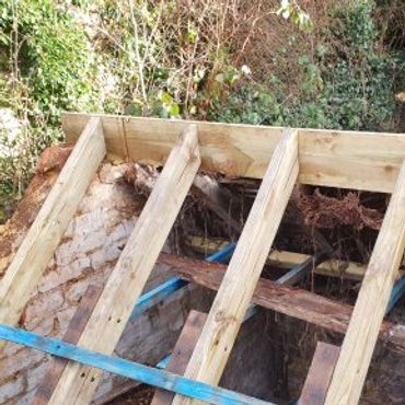 Wooden beams installed on a roof under construction in a natural setting.