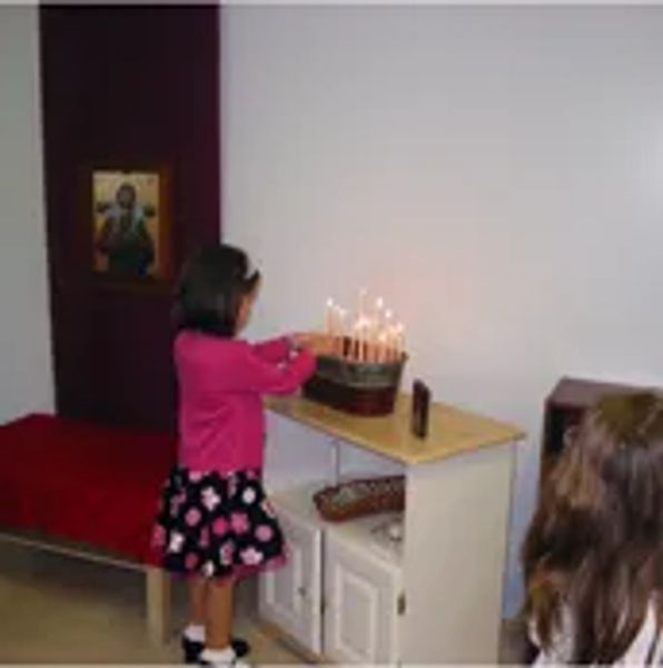 A child lighting candles on a menorah in a room with religious decor.