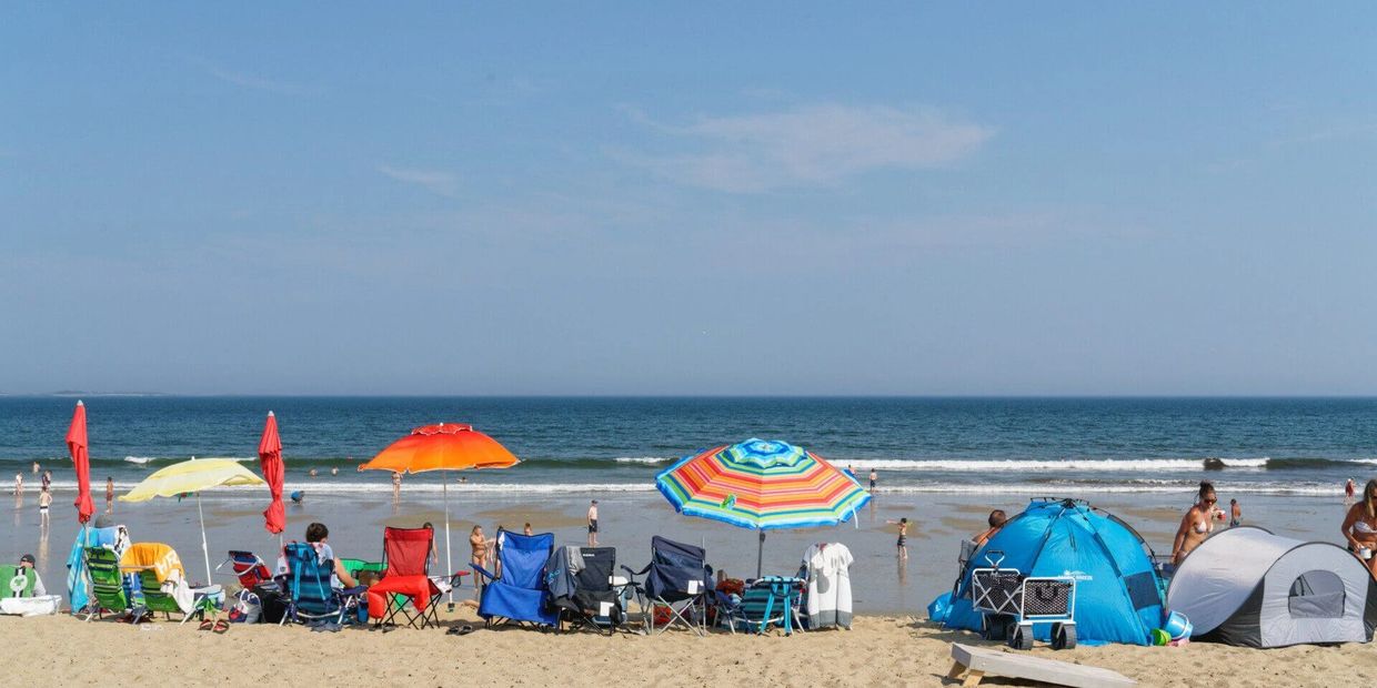 Families relaxing under umbrellas at Old Orchard Beach.