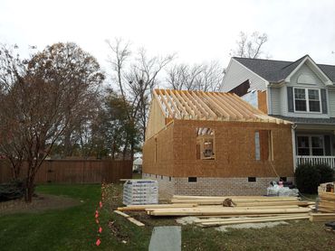 Wooden frame addition under construction beside a house.