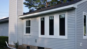 A blue house with white-framed windows and a chimney.
