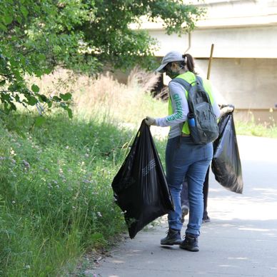 A volunteer holding two large bags while walking and cleaning up