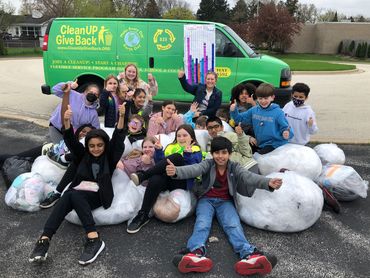 A second-grade class sitting on a pile of plastic bags they collected for earth month to recycle