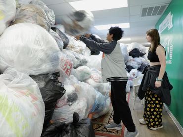 two teenagers adding to a giant wall of plastic bags, covering over half of a 2200 square foot room