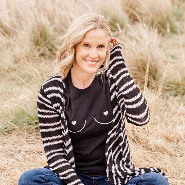 Kelly Euperio, IBCLC sitting in field, smiling, lactation consultant serving Colorado