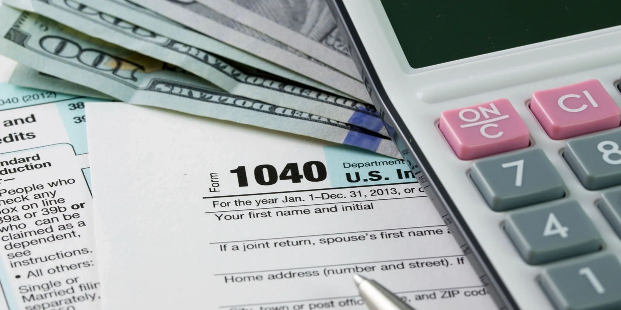 U.S. tax form 1040 with cash and calculator.