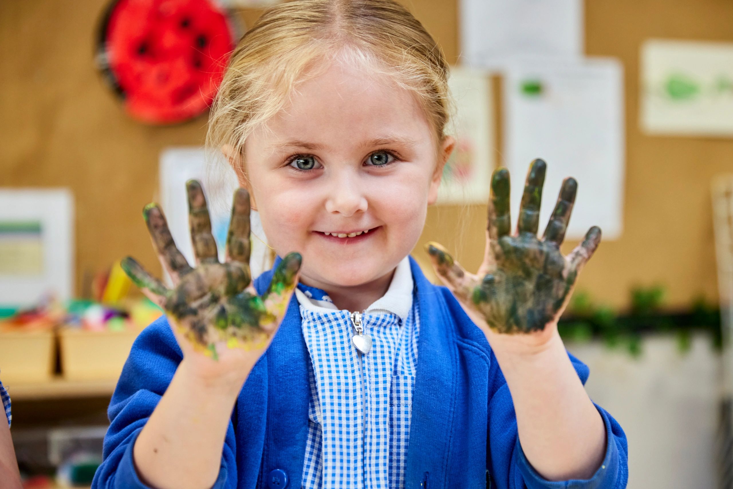Smiling girl with paint-covered hands showing her creativity.