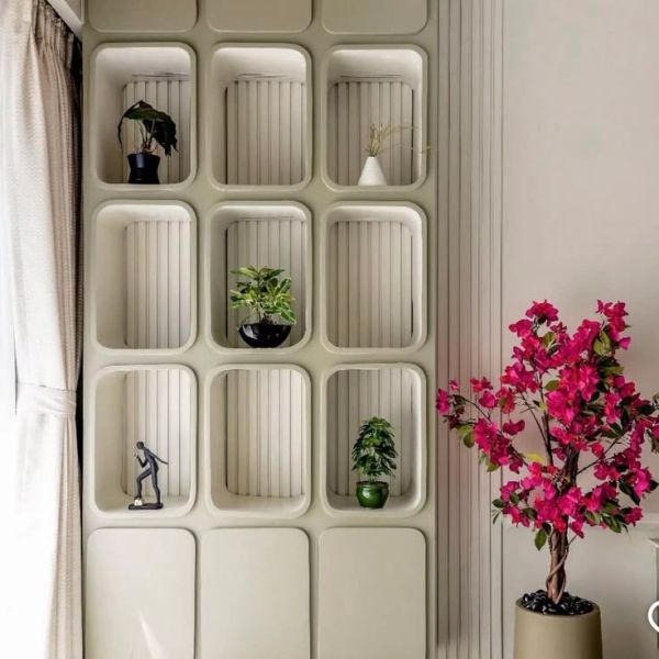 Modern wall shelf with plants and decor beside a pink flowering plant.