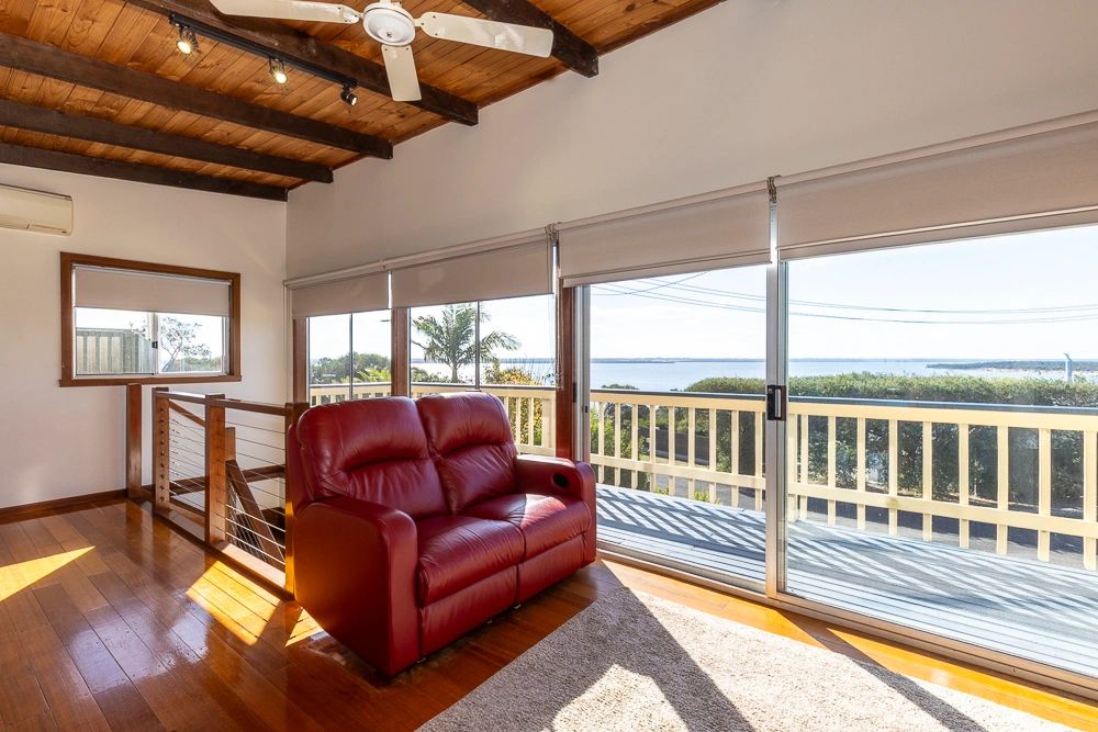 A cozy living space with a red leather loveseat and a panoramic view of the water.