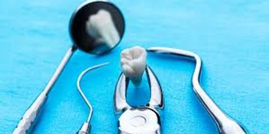 Dental tools including a mirror, explorer, forceps, and scaler on a blue cloth.