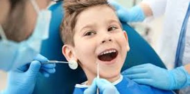 A boy smiling during a dental checkup with a dentist.