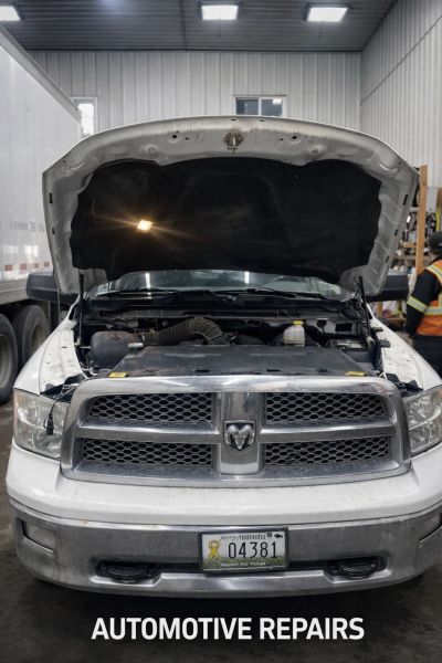 White Dodge truck with hood open in repair shop.