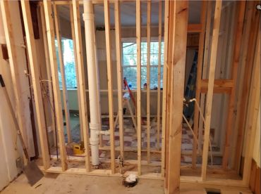 Interior view of a house under construction with wooden frames and plumbing.