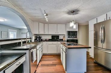 Modern kitchen with white cabinets and stainless steel appliances.
