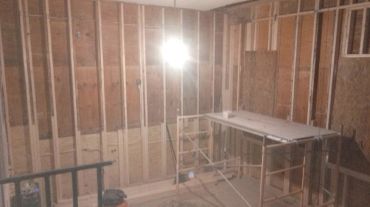 Room under construction with exposed wooden framing and scaffolding.