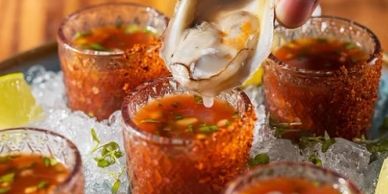 Fresh oysters being dipped into spicy cocktail sauce on ice.