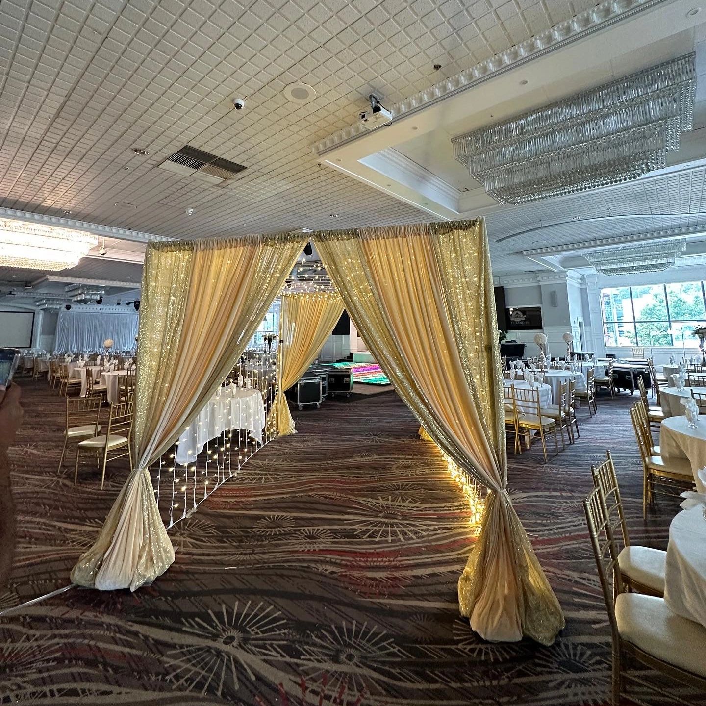 Elegantly decorated banquet hall with golden drapes and fairy lights.