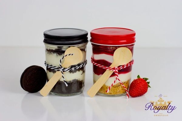 Two layered desserts in jars with spoons and toppings.