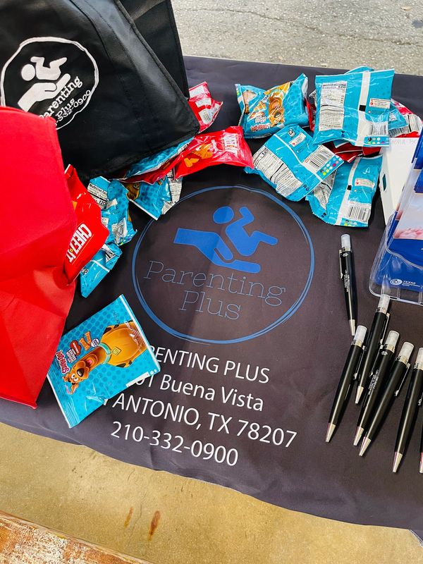 Parenting Plus Outreach Table supplies set up on table with banner, pens and snacks