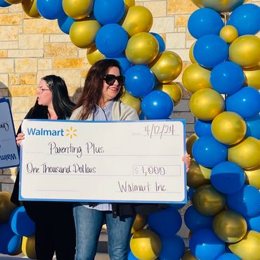 Parenting Plus's Gena Meyer in front of a Walmart with large check for $1,000 donation