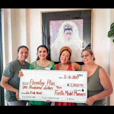 Parenting Plus us supported by community members holding a large check for $1,000