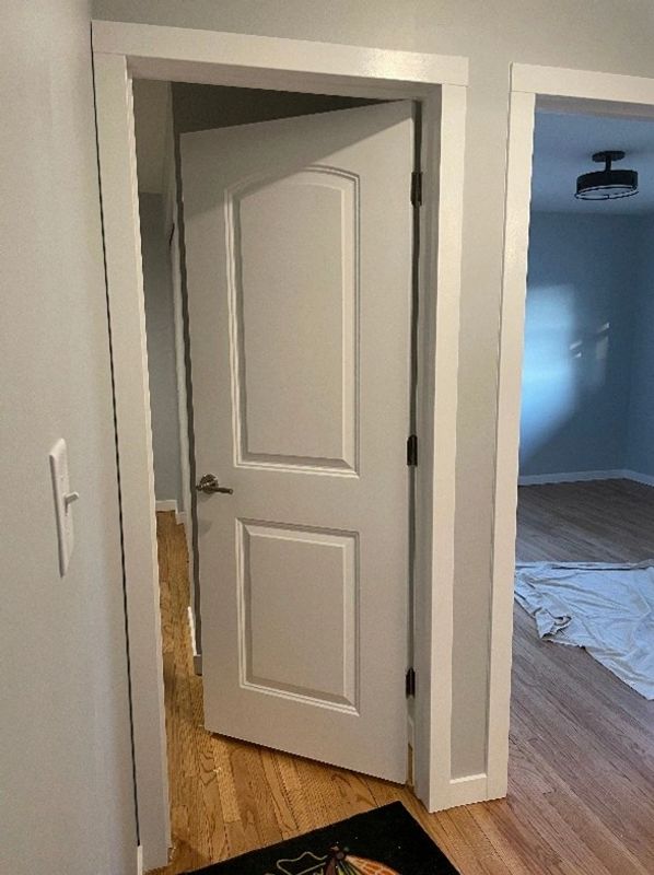 A white door installed crookedly, not aligned properly with the frame.
