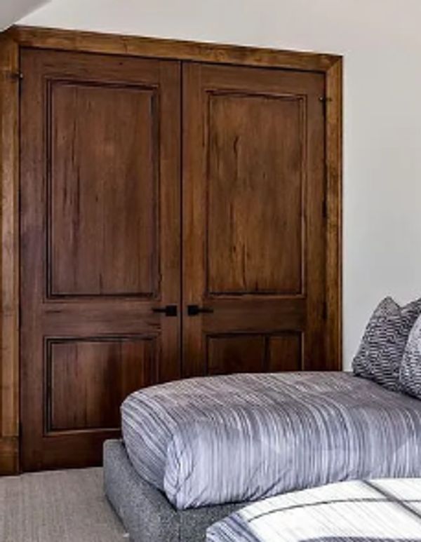 Wooden double doors in a bedroom with a sloped ceiling.