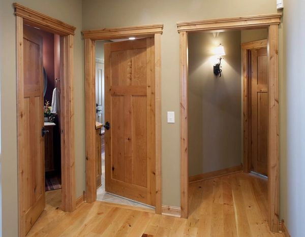Three wooden doors in a hallway with hardwood floors and soft lighting.
