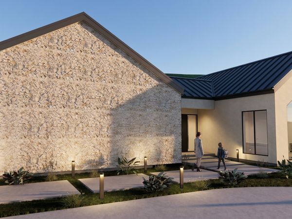 Modern house exterior with stone wall and pathway lighting at dusk.