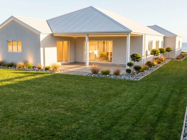 Modern white house with a spacious green lawn and minimalist landscaping.