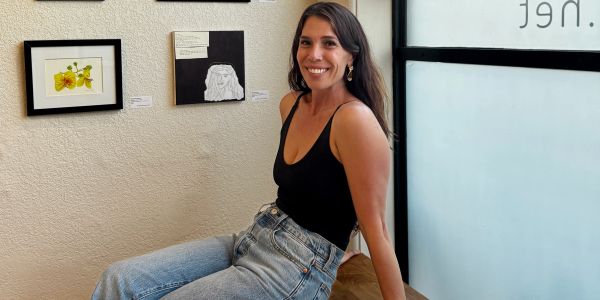 Woman sitting and smiling indoors by artwork.