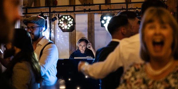 DJ playing music at a lively party with dancing guests.