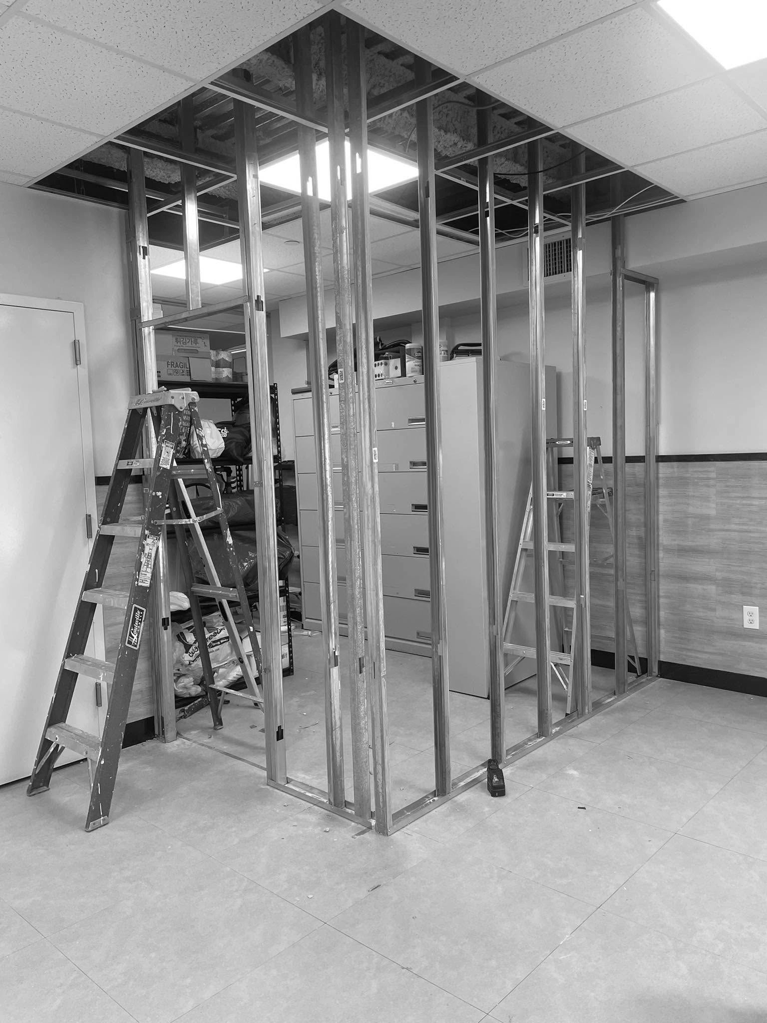 Metal frame construction for a new wall inside an office space with ladders around.