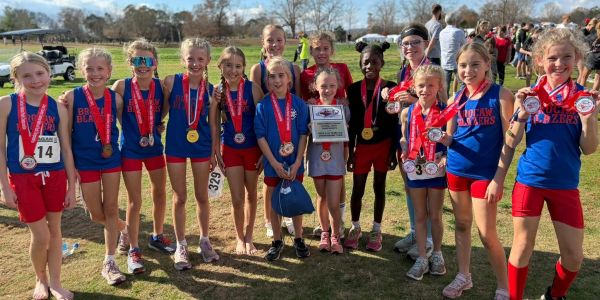 Young girls in sports medals posing outdoors.