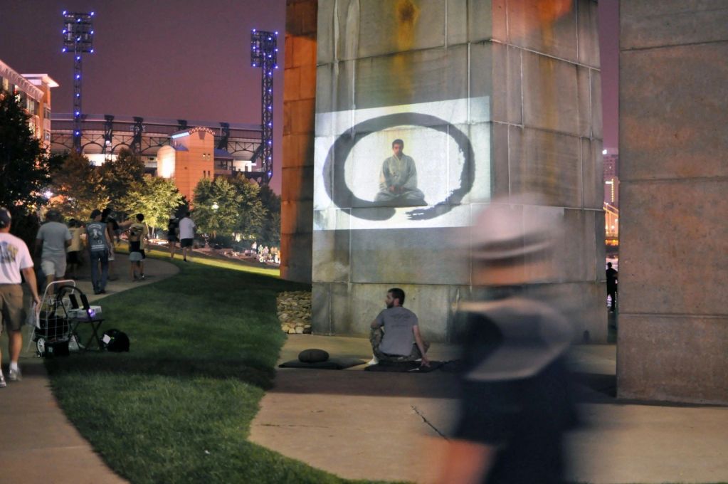 Night scene with people walking near a projected image on a wall.