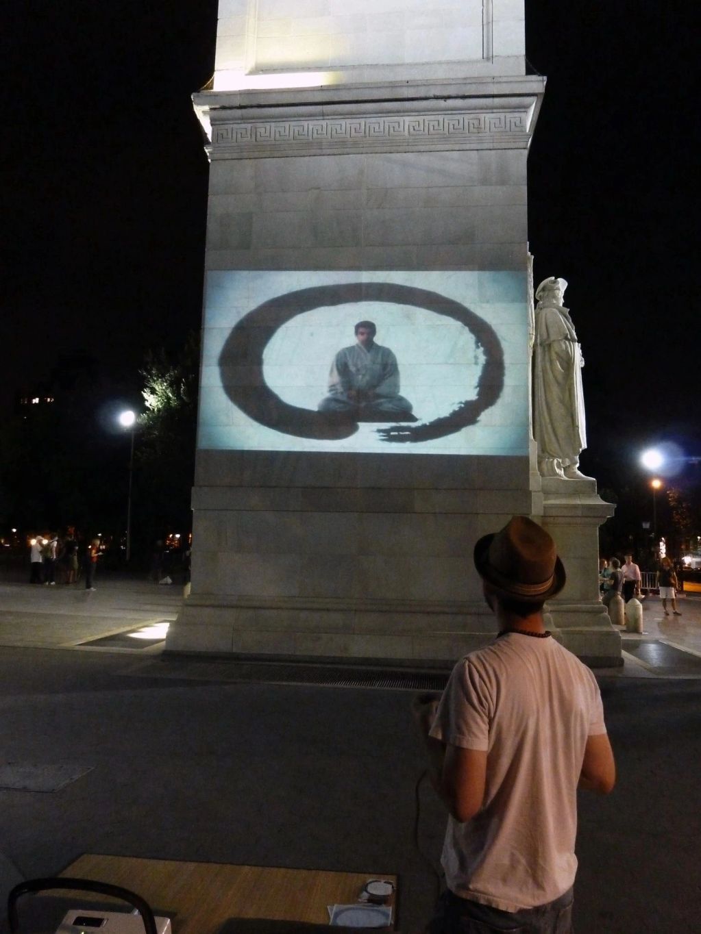 Person watching a meditation video projected on a monument at night.