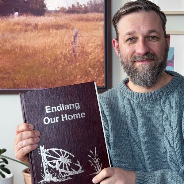 Man holding a book titled 'Endiang Our Home.'