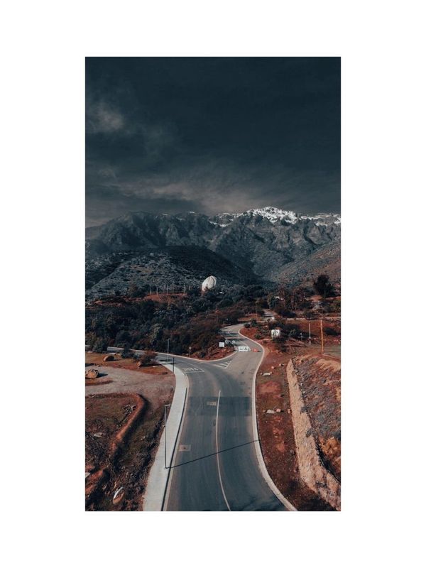 Winding road leading to mountainous terrain under a dark sky.
