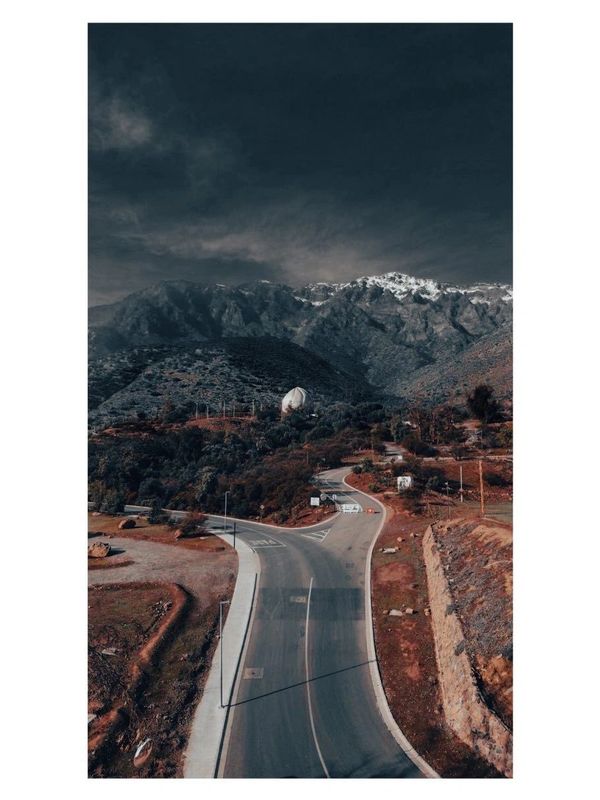 Winding road leading to mountainous terrain under a dark sky.