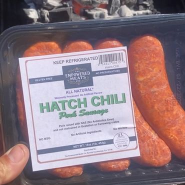 Package of Hatch Chili Pork Sausage held outdoors near a fire pit.