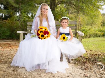 A bride and her flower girl sitting in a swing.