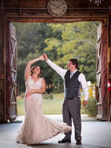 A bride and groom dancing in front of our barn doors inside our barn wedding venue.