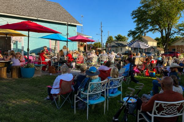 People enjoying an outdoor gathering under colorful umbrellas on a sunny day.