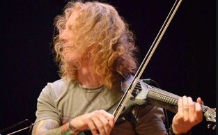 man with long hair playing electric violin

