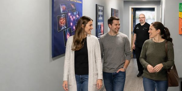 Patients walking through the clinic hallway with Dr. Lambert in the background.